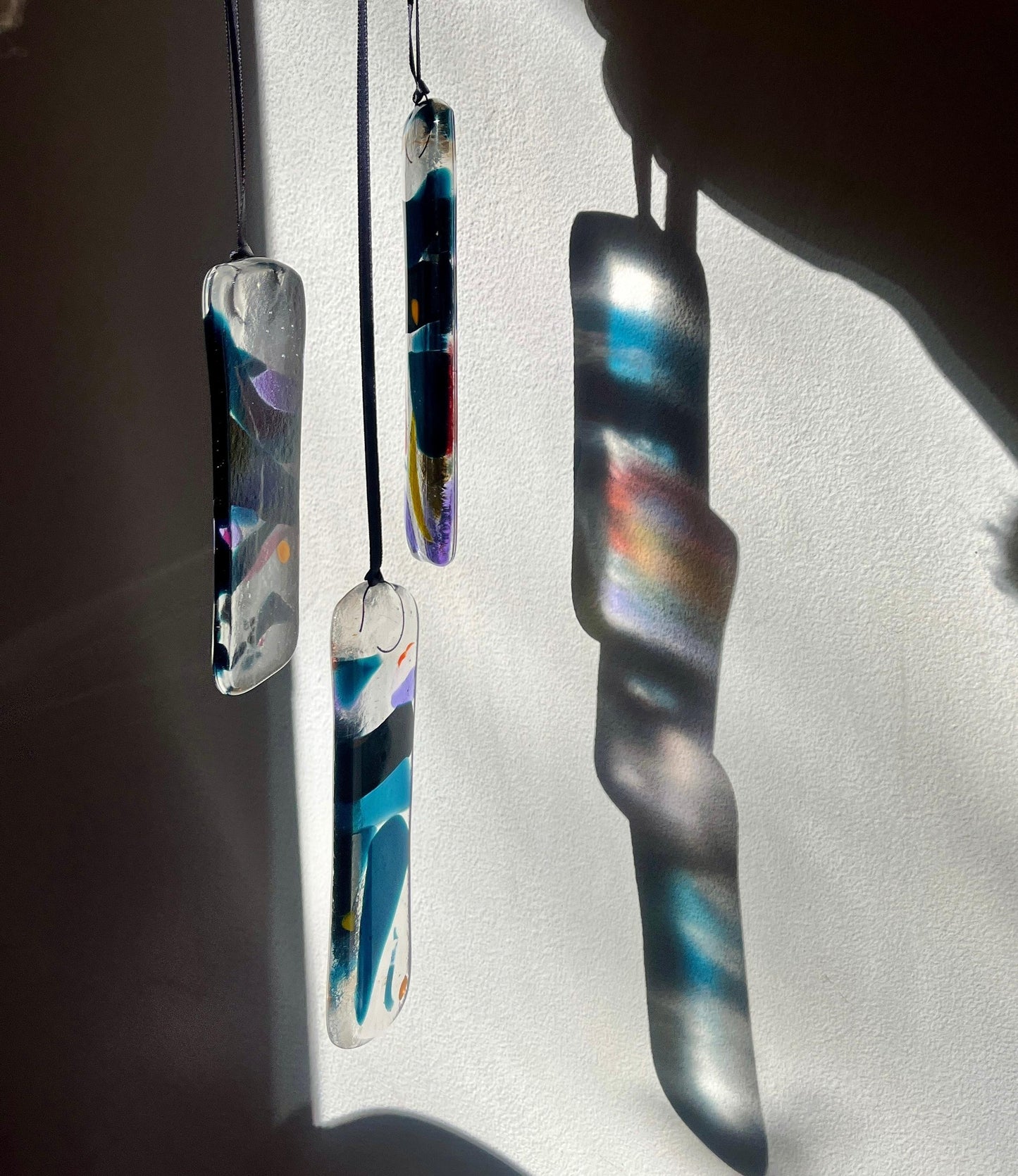 Colorful glass pendants hanging against a white wall.