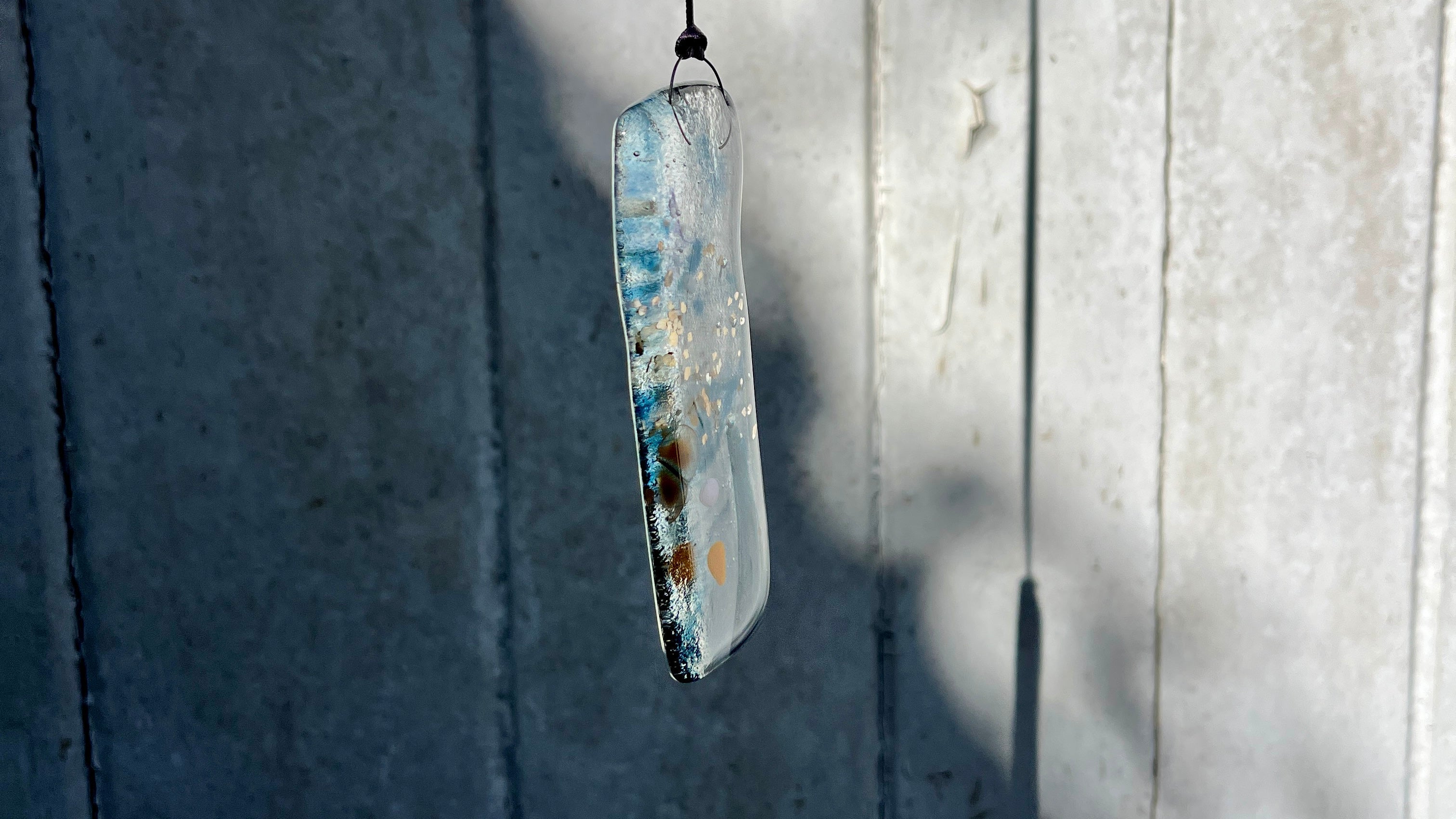 Decorative pendant by Bryony Lane with a textured surface hanging against a wooden background