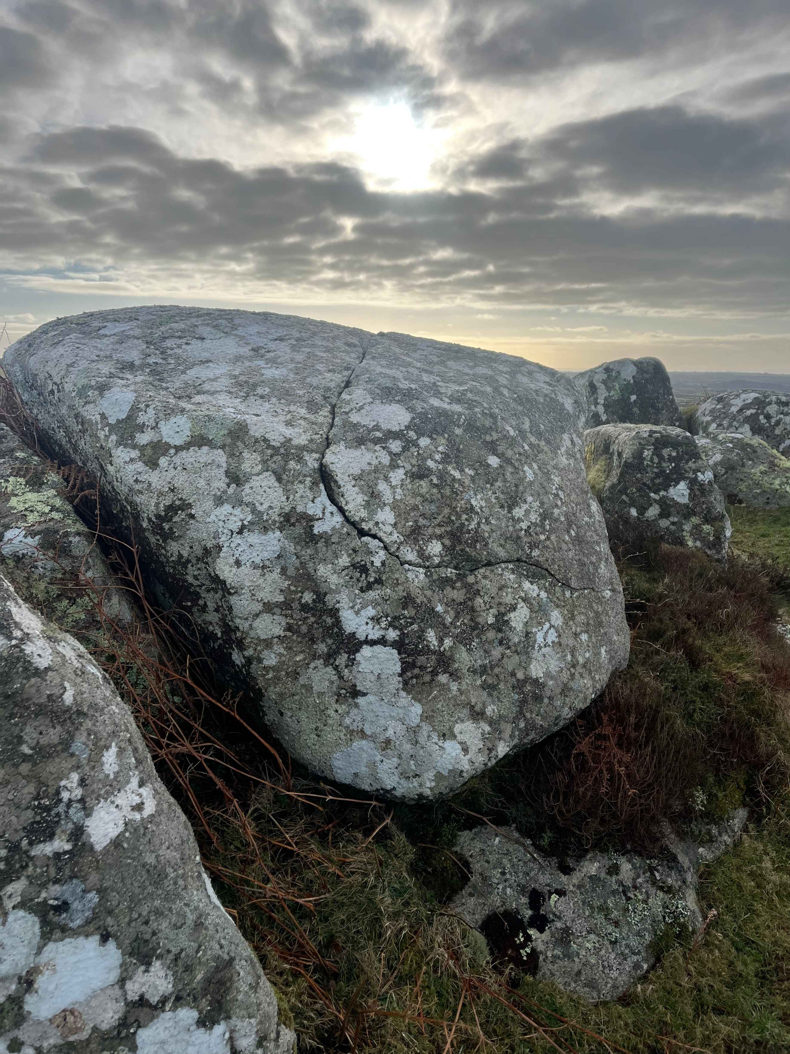 Large lichen-covered rock with a cloudy sky in the background