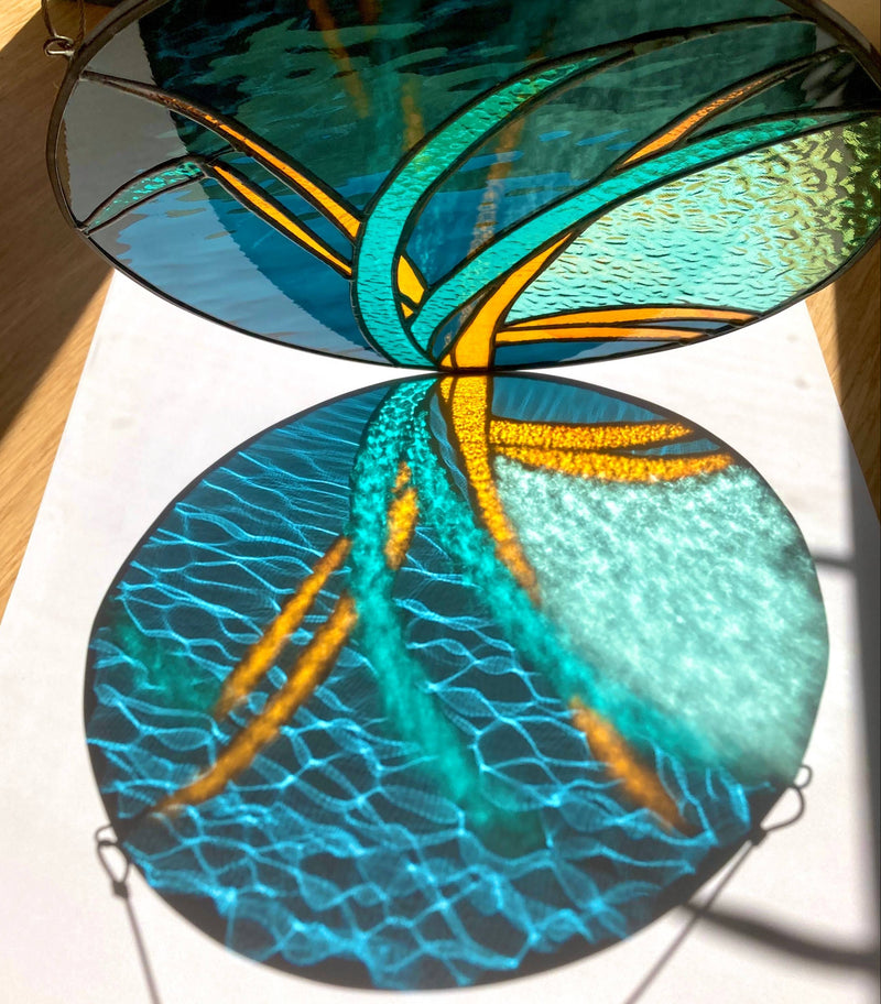 Two circular stained glass panels with blue and orange design on a white surface.
