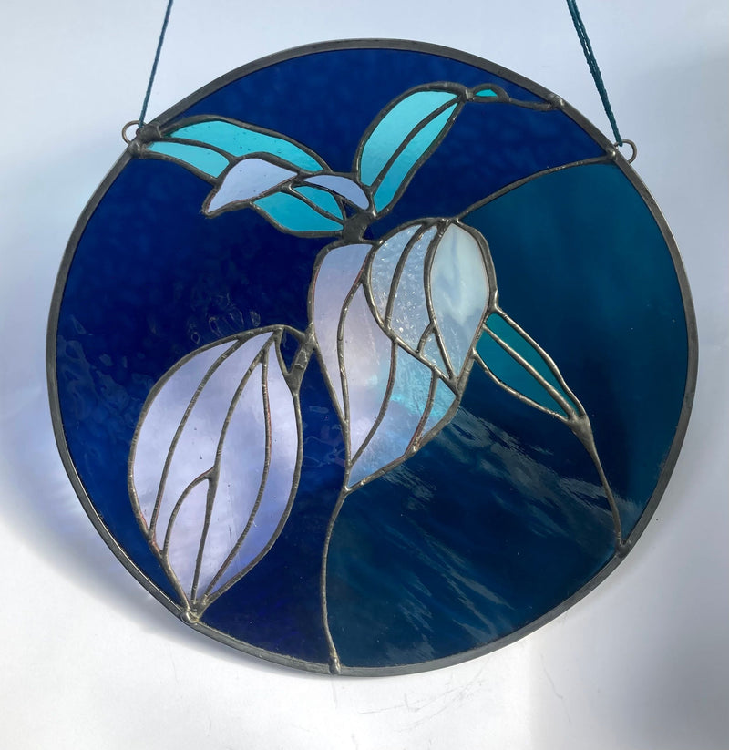 Stained glass panel with leaf design on a blue background