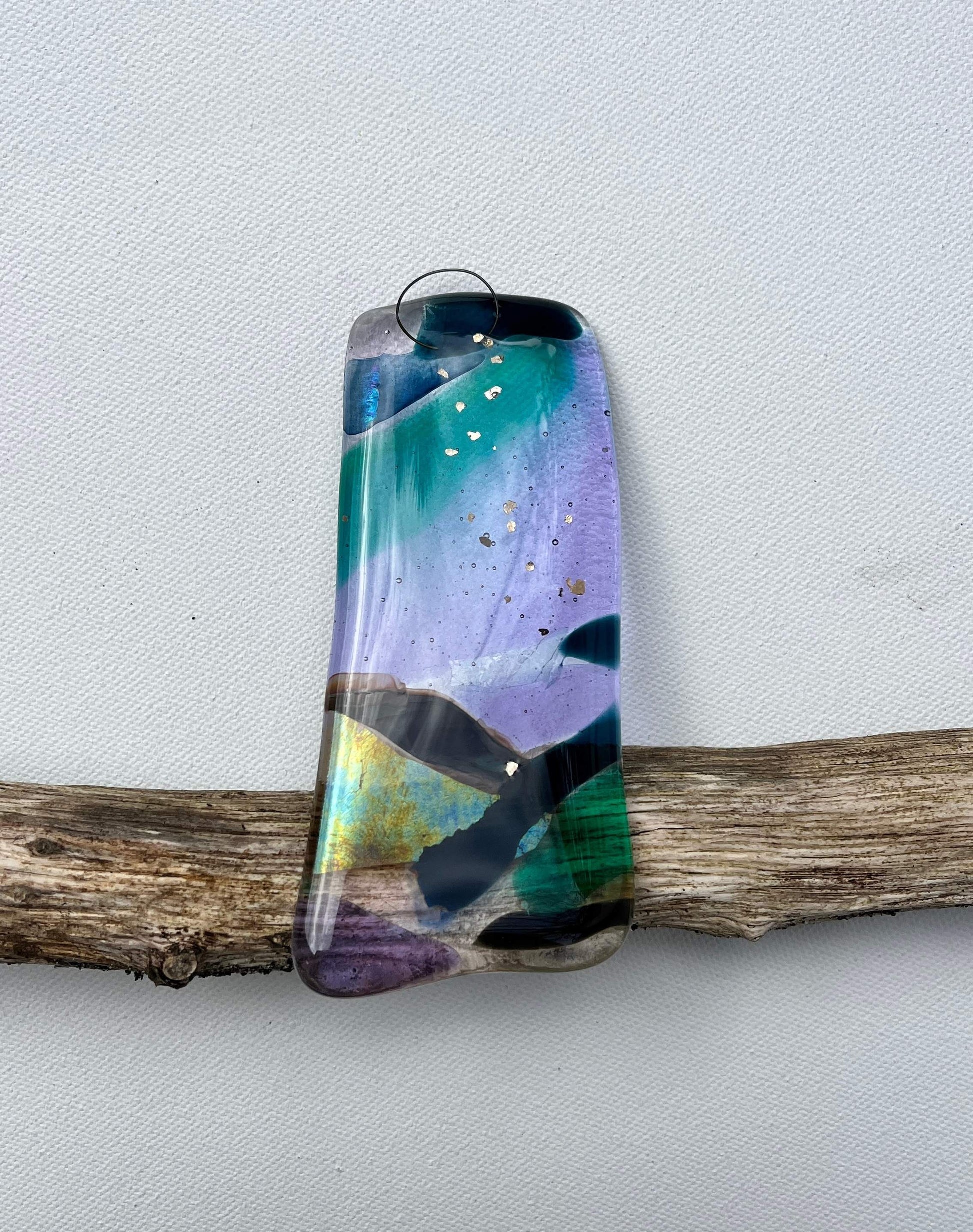 Colorful pendant on a branch against a light gray background