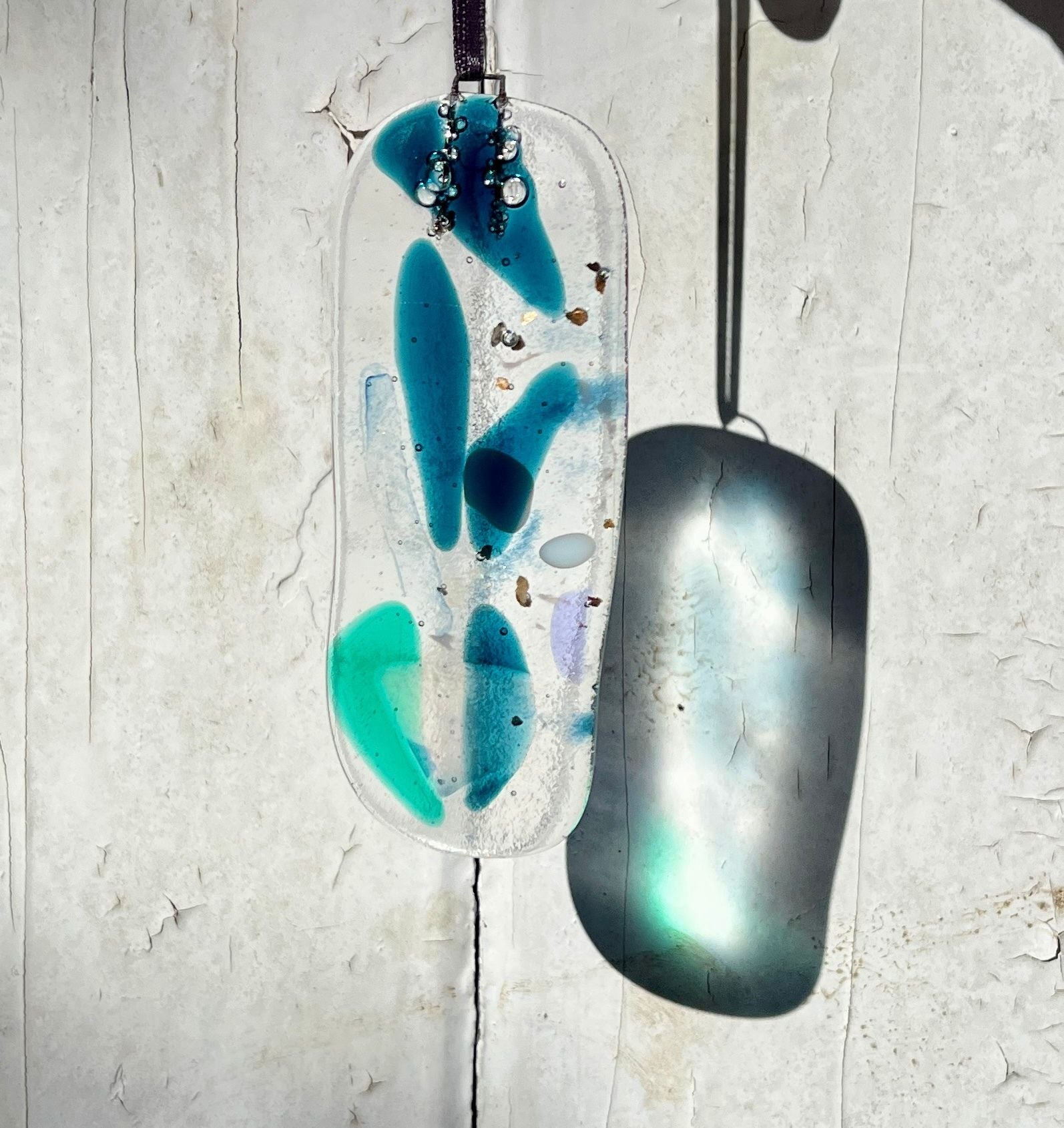 Decorative pendant with blue and green design on a textured surface