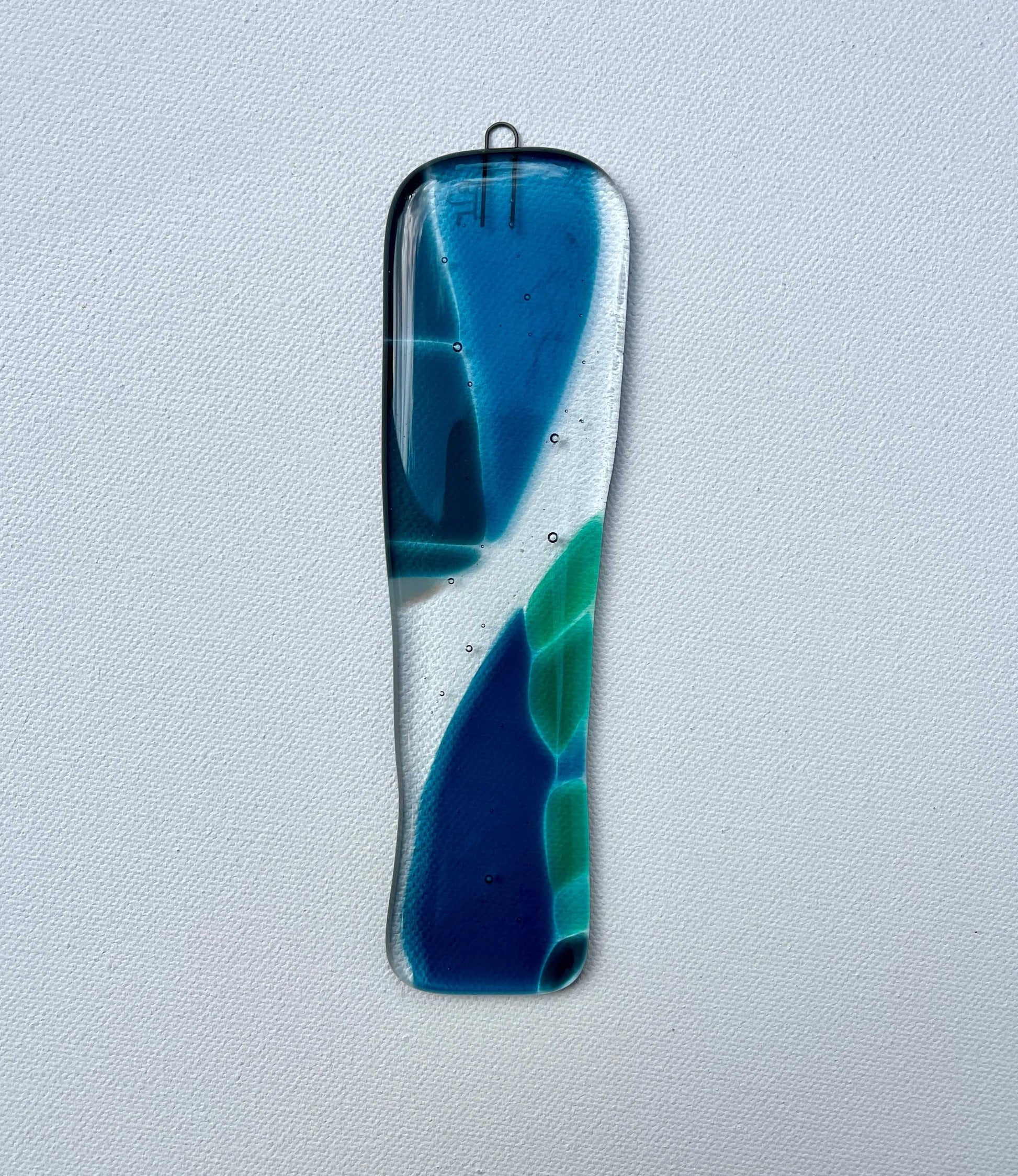 Decorative glass panel with blue and green swirls on a light gray background